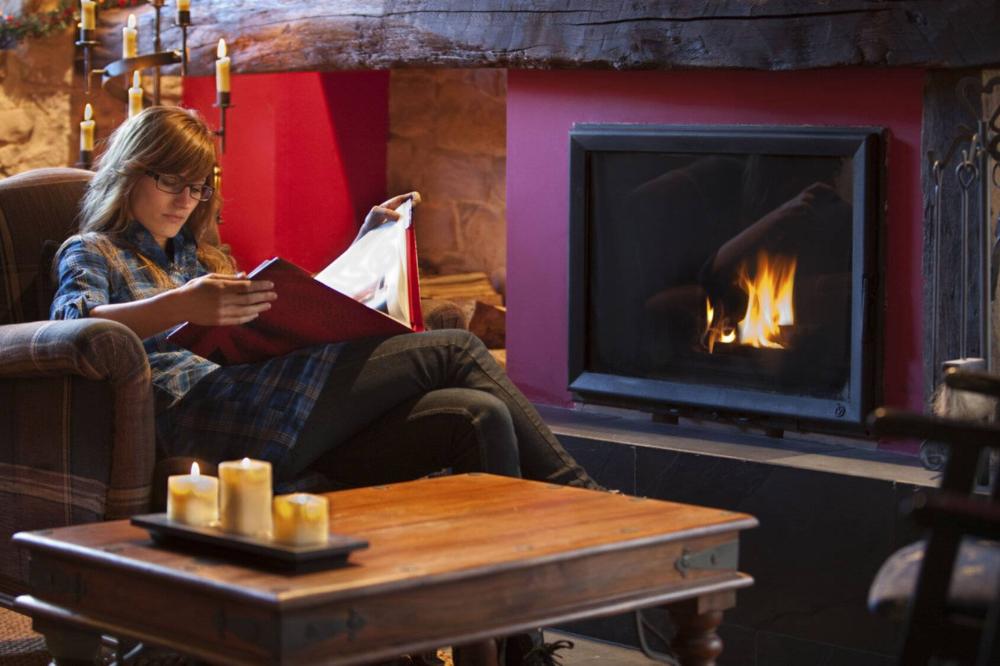 Chica leyendo junto a la chimenea